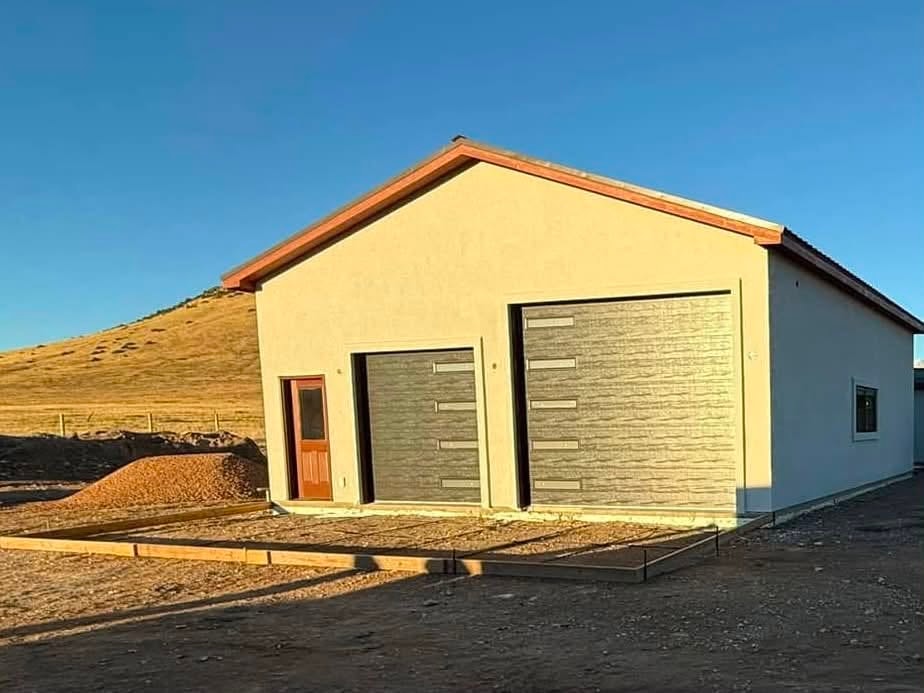 Completed garage with stucco exterior and double modern garage doors against a Colorado hillside